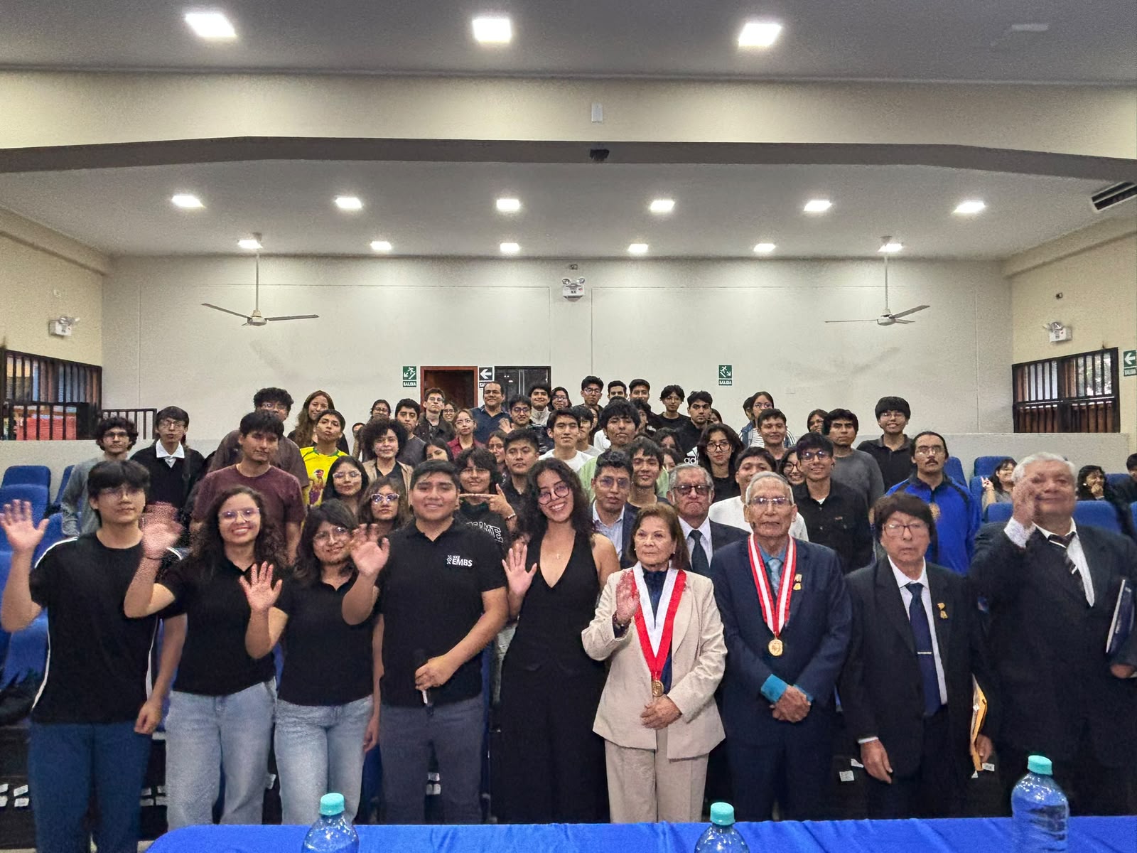 Asistentes saludando en una charla presencial